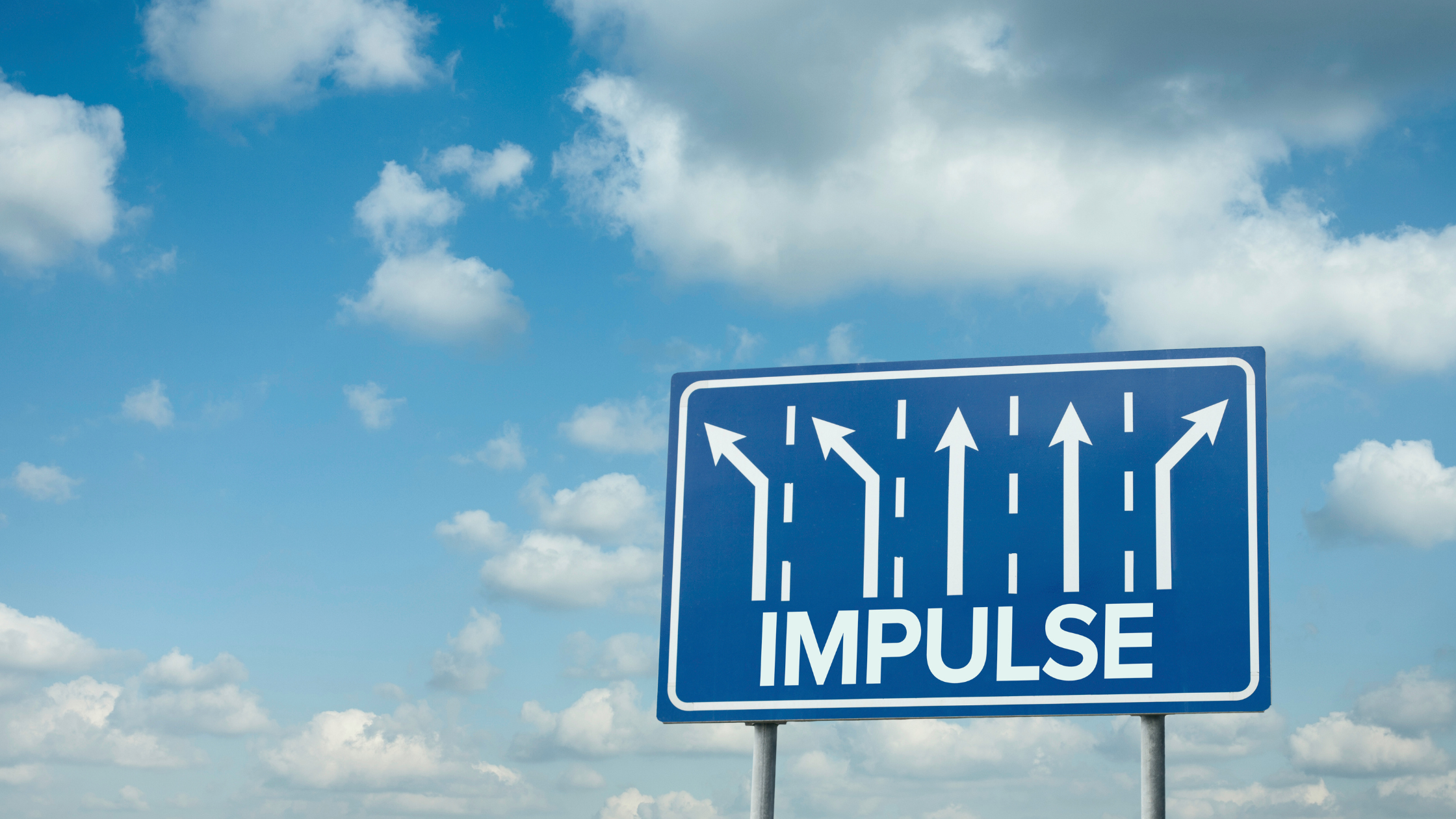Highway road sign with the word “IMPULSE” and multiple arrows, symbolizing choices and directions, under a bright sky with clouds.
